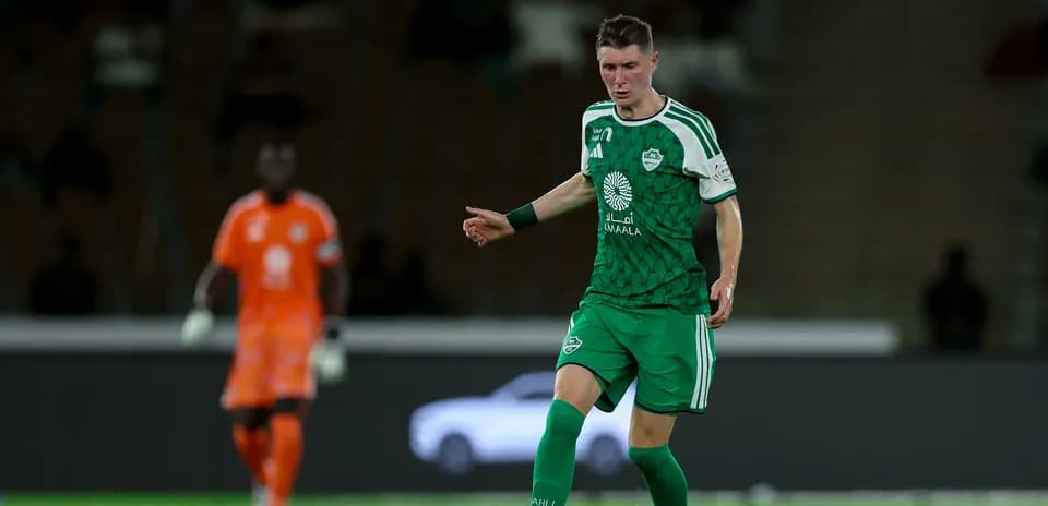 Joueur en maillot vert dribblant sur le terrain