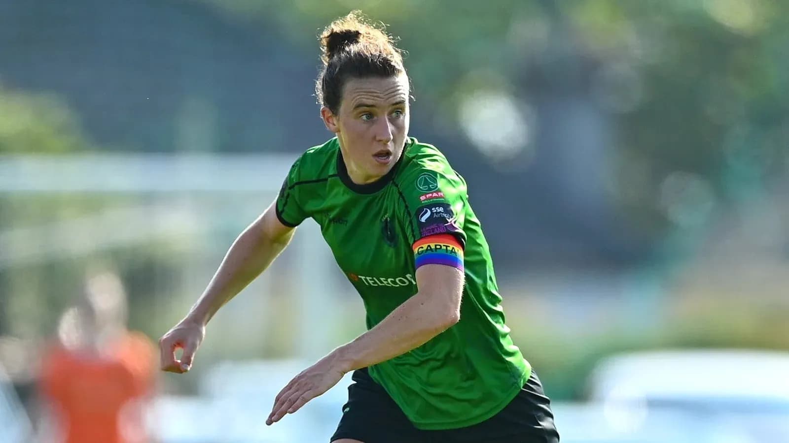 Joueuse en action avec un maillot vert et brassard