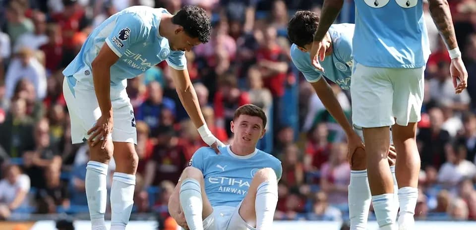 Joueur de Manchester City assis, blessé, entouré par des coéquipiers