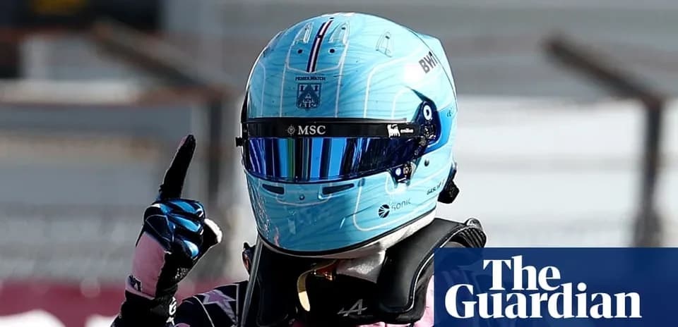 Pilote de Formule 1 avec un casque bleu levant le doigt