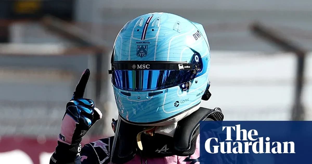 Pilote de Formule 1 avec un casque bleu levant le doigt