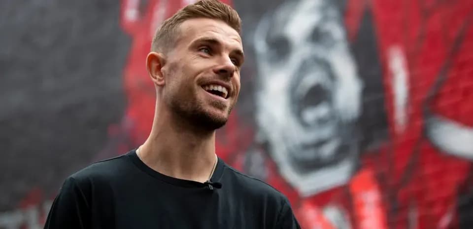 Joueur souriant devant une fresque murale rouge