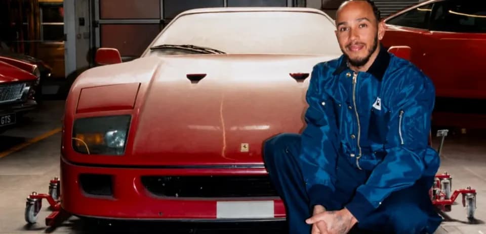Homme posant devant une Ferrari rouge dans un garage