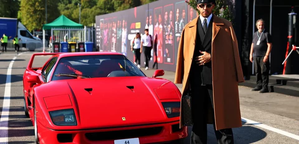 Homme en costume devant une Ferrari rouge