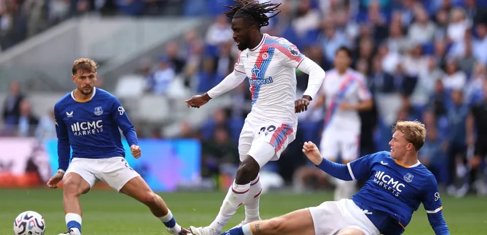 Joueur de Crystal Palace dribble entre deux joueurs d'Everton
