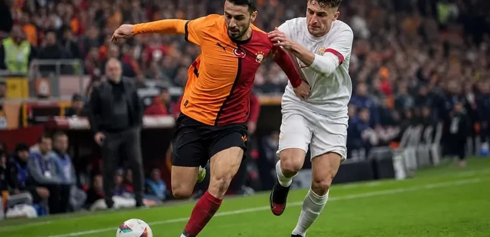 Joueur de Galatasaray dribblant sous pression d'un adversaire