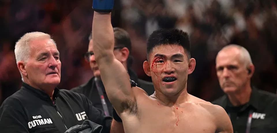 Fighter celebrating victory with bloodied face in octagon