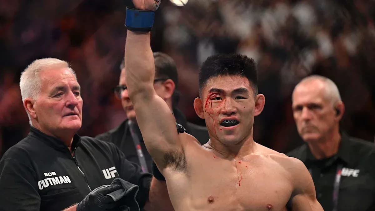 Fighter celebrating victory with bloodied face in octagon