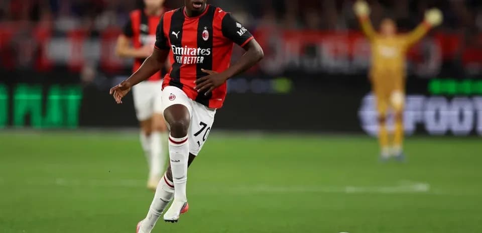 Joueur du Milan AC courant avec le ballon sur terrain