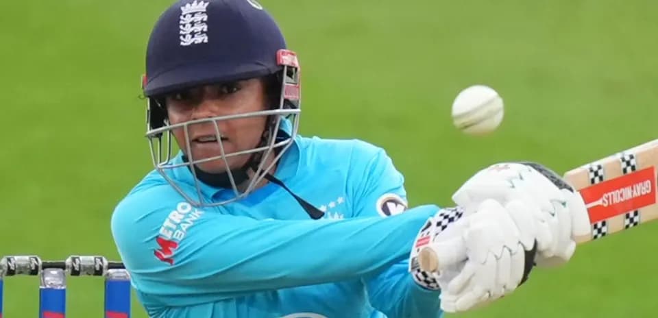 Joueuse frappant la balle de cricket au stade