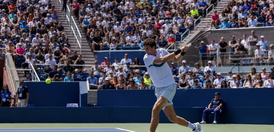 Joueur de tennis frappant une balle devant un public