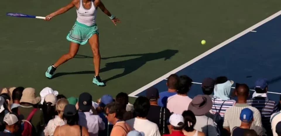 Joueuse de tennis frappant une balle devant un public