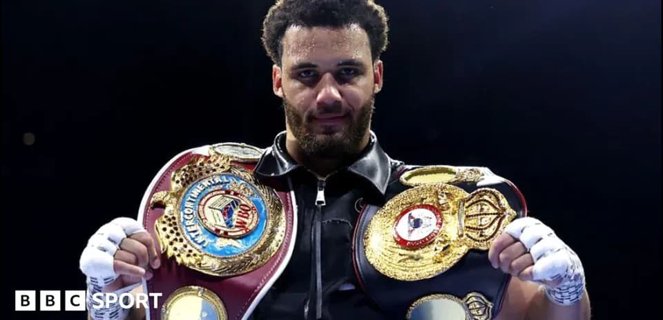 Boxeur tenant deux ceintures de champion sur le ring