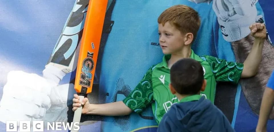 Enfant posant avec une batte de cricket orange