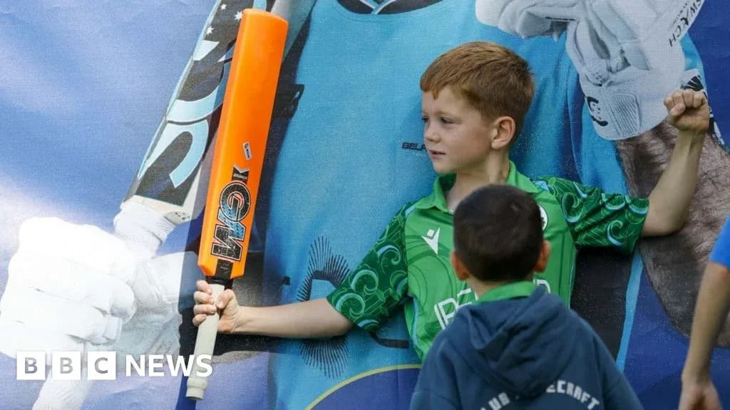 Enfant posant avec une batte de cricket orange