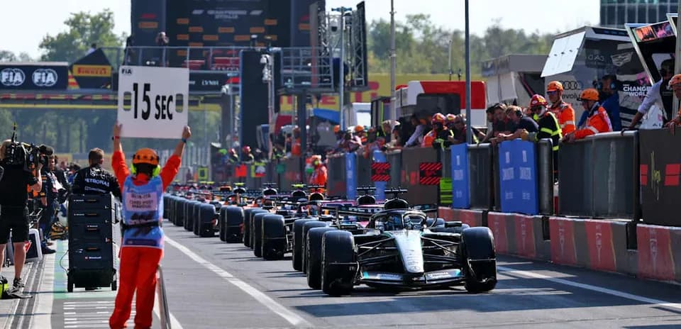 Pilotes de Formule 1 en pit lane avec panneau de 15 secondes