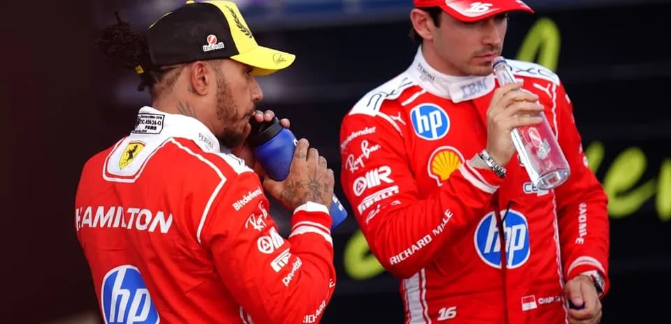 Deux pilotes en tenue Ferrari buvant de l'eau