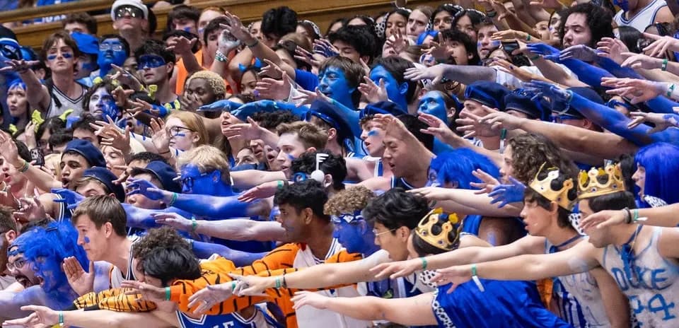 Supporters en costume bleu agitant les bras dans les gradins