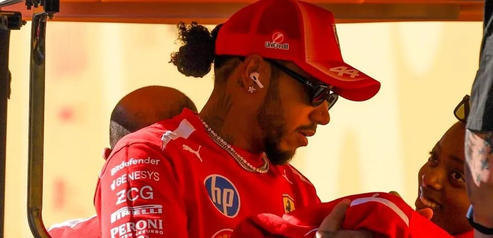 Pilote en tenue Ferrari discutant avec une personne