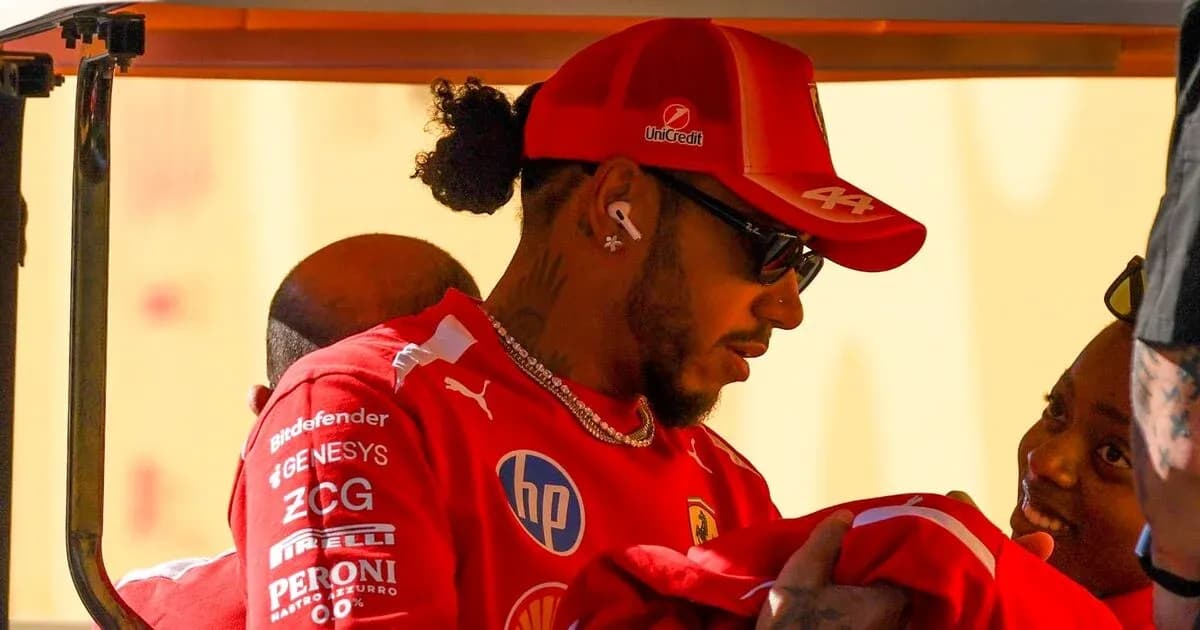 Pilote en tenue Ferrari discutant avec une personne