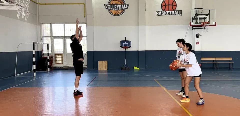 Un entraîneur montrant un tir au panier à deux joueuses