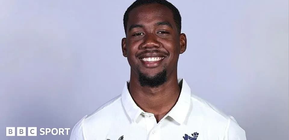 Joueur de cricket souriant en uniforme blanc