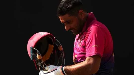 Joueur de cricket tenant son casque en regardant vers le bas