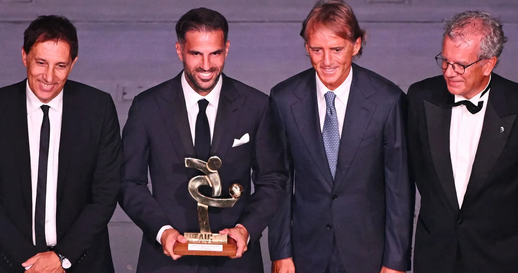 Quatre hommes posant avec un trophée lors d'une cérémonie