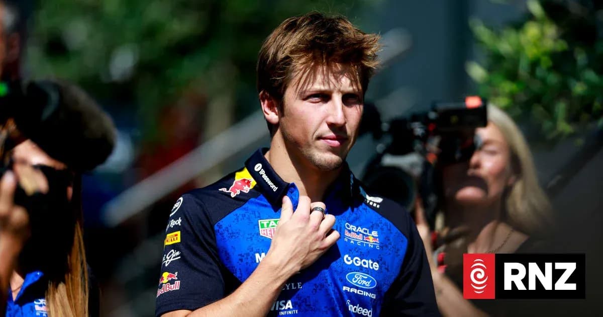 Pilote de Formule 1 en tenue d'équipe, regardant autour Pilote de Formule 1 en tenue d'équipe, regardant autour