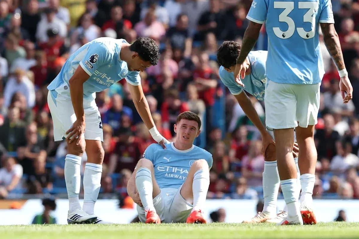 Joueur de Manchester City assis, blessé, entouré par des coéquipiers Joueur de Manchester City assis, blessé, entouré par des coéquipiers