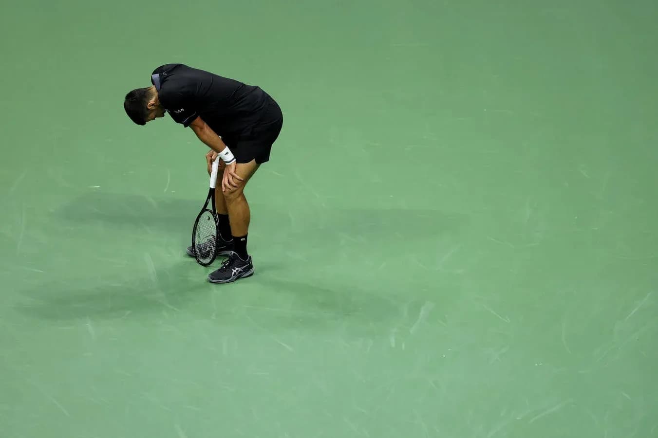 Joueur de tennis se penchant sur le court vert Joueur de tennis se penchant sur le court vert