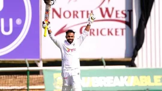 Batter celebrating century with raised bat on field Batter celebrating century with raised bat on field