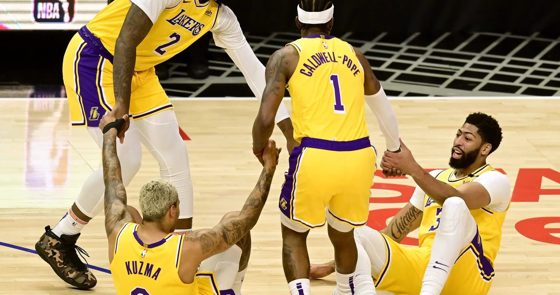 Joueurs des Lakers aidant Kuzma et Davis au sol Joueurs des Lakers aidant Kuzma et Davis au sol